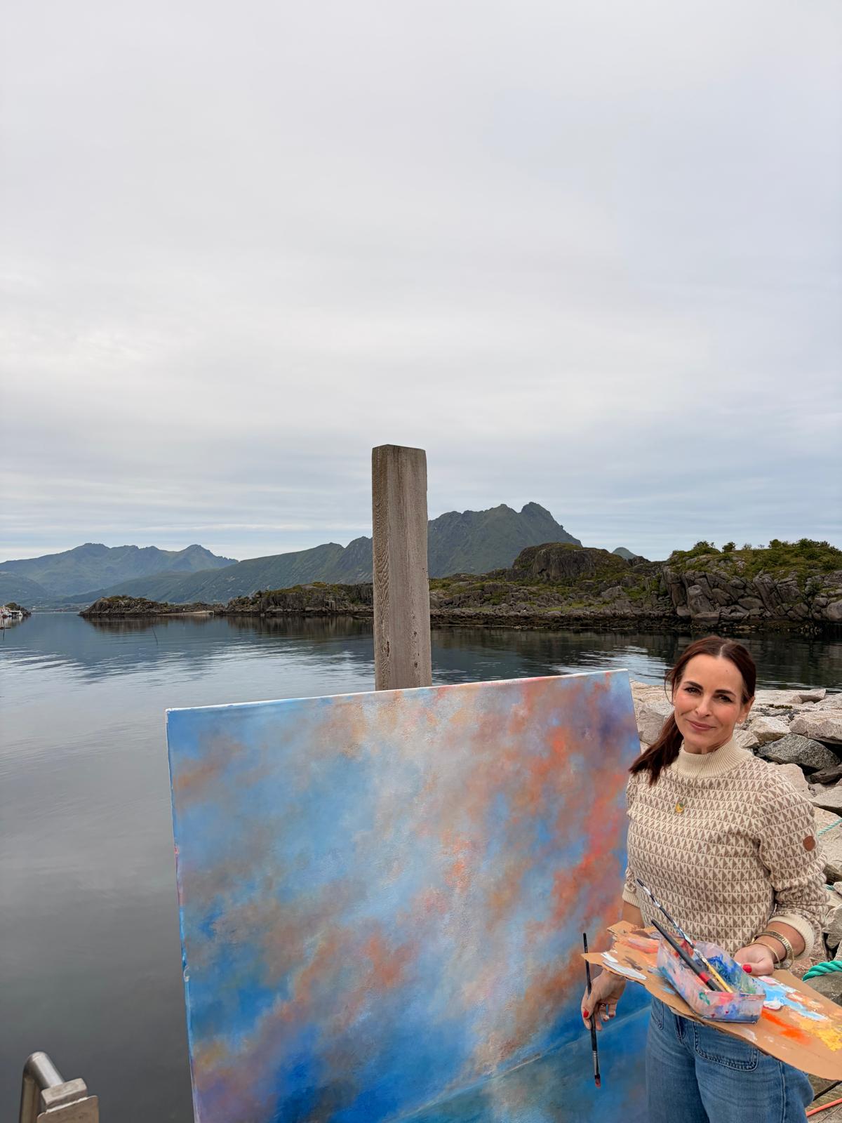 An artist painting on a wooden pier in Lofoten